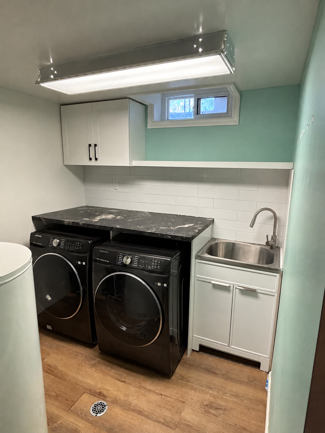 Laundry room with black washer and dryer, white cabinets, sink and retouched wall paint