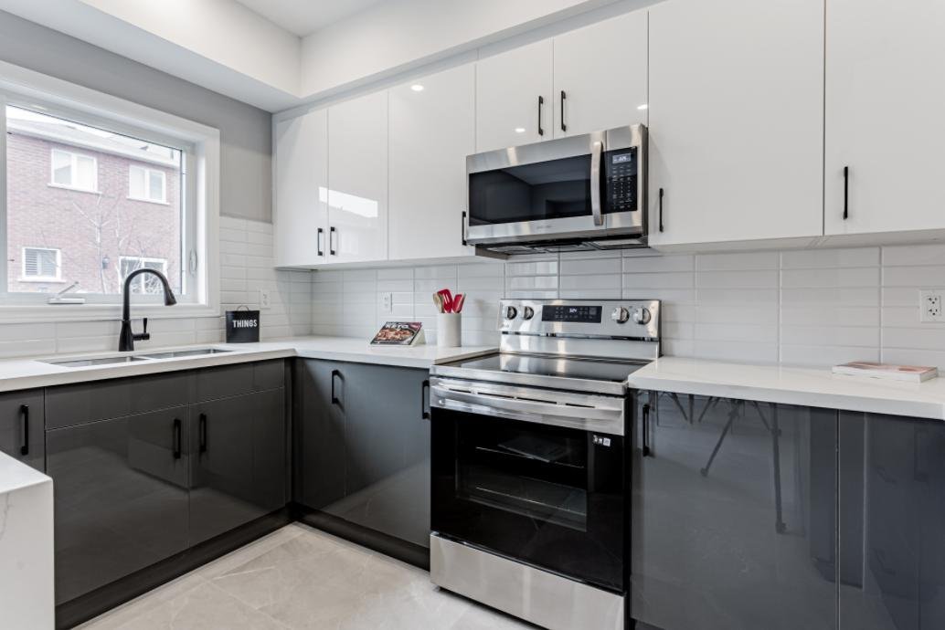 Two-tone kitchen with glossy white upper cabinets and charcoal lower cabinets
